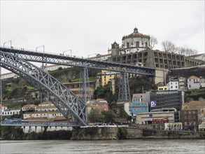 Wide angle shot of a city with a large steel bridge over a river and historic buildings on a hill,