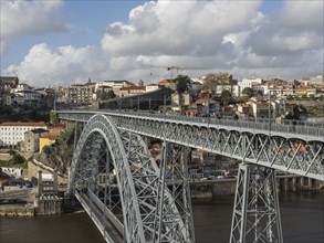 Panoramic view of a bridge crossing a city with clouds and sky in the background, Porto, Douro,