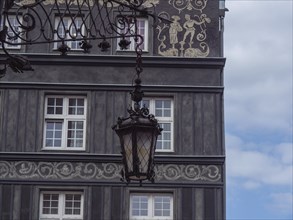 Facade of an old building with decorative reliefs, windows and an antique wall lantern, Gdansk,