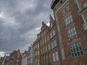Row of tall, brick historic buildings with many windows under a cloudy sky, Gdansk, Poland, Europe