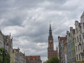 Historic buildings with a large tower clock and street lamps, under a cloudy sky, Gdansk, Poland,