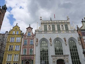 Several historic buildings with colourful, decorated facades under a cloudy sky, Gdansk, Poland,