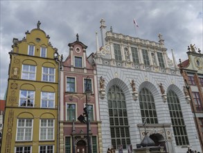 View of historical buildings with decorated facades and sculptures under a cloudy sky, Gdansk,