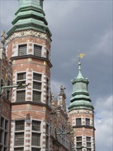 Historic buildings with distinctive towers and decorations under a cloudy sky, Gdansk, Poland,