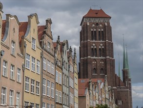 Historic buildings and a striking church tower under a cloudy sky, Gdansk, Poland, Europe
