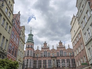 Historic buildings with an ornate church tower and a cloudy sky, Gdansk, Poland, Europe