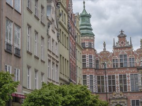 Historic buildings with ornate facades and a green roof under a cloudy sky, Gdansk, Poland, Europe