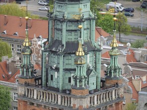 Towers of a historic clock tower with golden decorations and green copper roof, Gdansk, Poland,