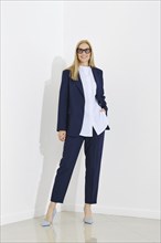 Full-length portrait of cute woman dressed in a chic navy blue suit with matching trousers and