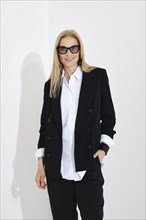 Medium closeup studio portrait of cute blonde woman in white shirt, black jacket and trousers