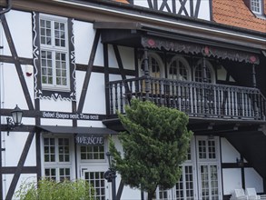Detailed view of a half-timbered house with an ornately decorated balcony, large windows and green