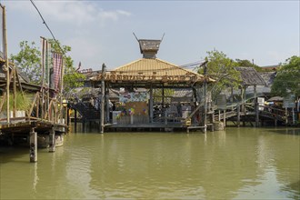 Traditional pavilion in the water on the floating market, surrounded by wooden houses and shops,