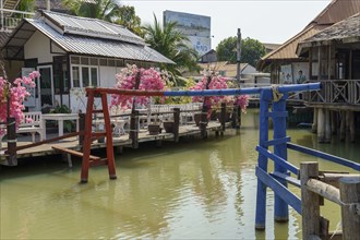 Traditional Thai houses on a quiet canal with colourful bridges and flowers, Pattaya, Thailand,