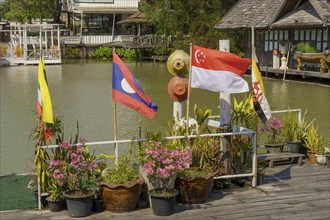 Various national flags and flower pots on the banks of a canal at the floating market, Pattaya,