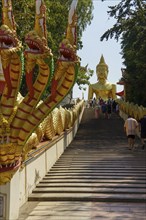 Golden Buddha statue at the top of a wide staircase, flanked by golden dragon figures, Pattaya,