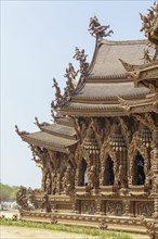 Close-up of a part of the wooden temple with detailed sculptures and decorations, blue sky,