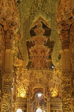 Interior view of an ornately carved wooden temple with magnificent golden elements, Pattaya,