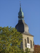 Close-up of a church tower with a clock and green dome in front of a blue sky, nottuln,