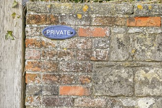 Red brick wall with 'private' sign on it