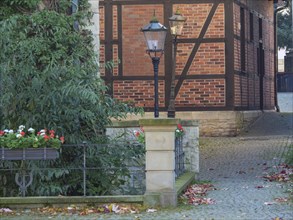 Half-timbered house with lanterns and plants in autumnal ambience, cobblestone path, quiet