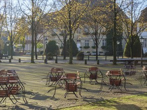 Deserted square in autumn with tables and chairs lined up under trees, nottuln, münsterland,