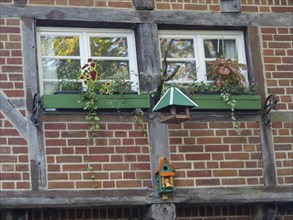 Flower-decorated windows of a half-timbered house with decorative birdhouses, nottuln, münsterland,