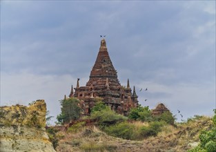 Brick stupa with behind green trees at the Irrawaddy river