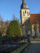 Historic church with clock on the tower, surrounded by an autumn garden and flowers, nottuln,