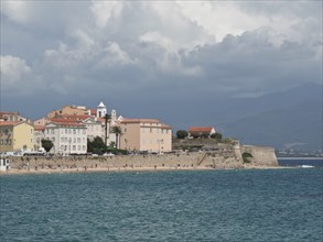 City with coastline and various buildings in front of a slightly cloudy sky, ajaccio, corsica,