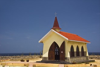 A bright yellow small Catholic chapel that stands on the hills above the north shore and to the