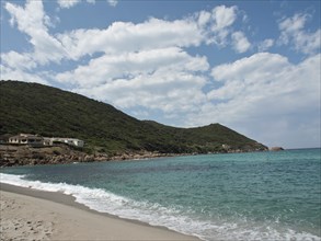 A wide sandy beach with gentle waves, surrounding hills and a loose woollen sky, ajaccio, corsica,