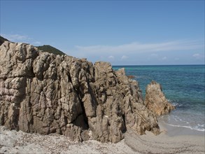 Rocky cliffs on a sandy beach with blue sea under a clear sky, ajaccio, corsica, france