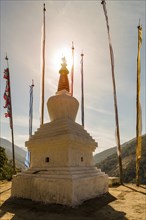 Sun setting behind the tip of an holy pagoda in the Kingdom of Bhutan