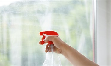 Employee cleaning window pane, spray water and soap, swab dusty and dirty glass, housework