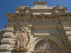 An elaborately decorated Tor tor of an old fortress with stone coats of arms and arches, all made