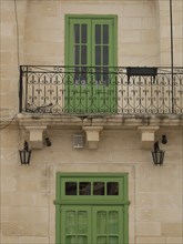 A green balcony with decorative lattice on a yellowish building, marsaxlokk, mediterranean sea,