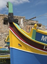 Colourful traditional boats in the harbour with historic stone walls in the background, marsaxlokk,