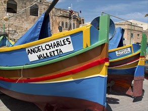 Multicoloured fishing boats parked in front of a historic building in Valletta, Malta, marsaxlokk,