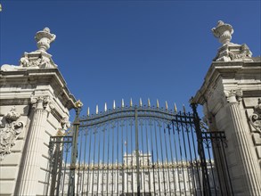 Large, decorated Tor tor with golden ornaments and columns leading to a historic building, Madrid,