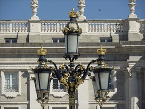 Decorative, golden street lamps in front of a richly decorated, historic, white building under a