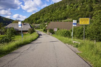 Entrance to the village with road, bus stop and village entrance sign to the Geschwend district,