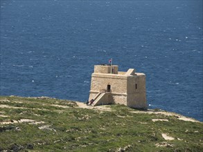 Historic watchtower on the coast with a view of the vast blue sea and clear sky, gozo,