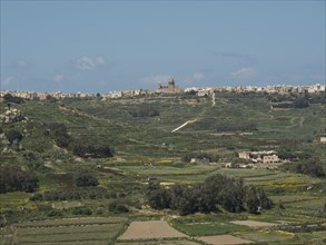 Spacious landscape with a church and scattered buildings on a hill, gozo, mediterranean sea, malta