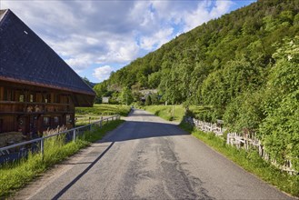 Access road with Black Forest house and old wooden fence to the historic district of Geschwend,