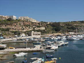 Mediterranean harbour with small fishing boats and yachts, surrounded by hills and modern