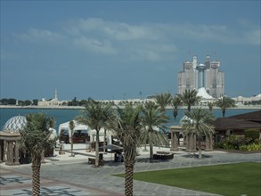 View of the beach and the sea with palm trees and resort buildings in the background, abu dhabi,