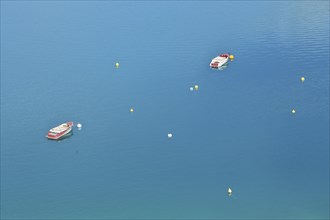 Two boats and buoys in the reservoir Lac de Sainte-Croix in the turquoise water near