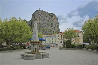 Fountain at Place Marcel Sauvaire with rock Le Roc, cliff, mountain, peak, Castellane, Provençal