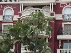 Red façade with several elegant balconies and lush plants, monte carlo, monaco, france