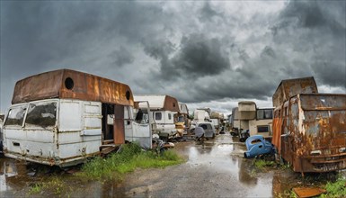 Abandoned vehicles and caravans under a cloudy sky, rust and rain, desolate ambience, symbol photo,